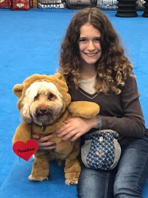 A girl holding a dog in a bear costume